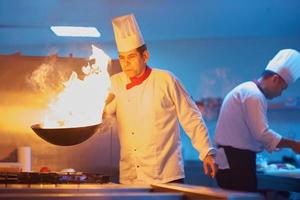 chef en la cocina del hotel prepara comida con fuego foto