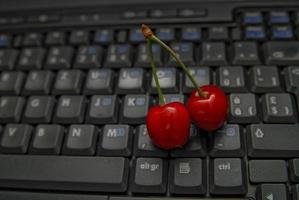 cereza fresca en el teclado del portátil foto