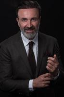 retrato de un elegante hombre de negocios de alto nivel con barba y ropa informal de negocios en un estudio fotográfico que ajusta el traje foto