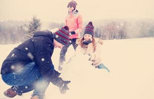 group of young people making a snowman photo