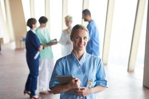 female doctor with tablet computer  standing in front of team photo