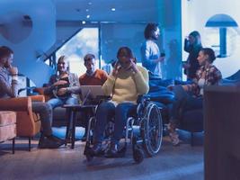 Portrait of disabled businesswoman in a wheelchair in front of her diverse business team at office photo