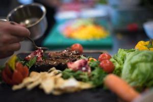 Chef hand finishing steak meat plate photo