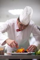 chef en la cocina del hotel preparando y decorando comida foto