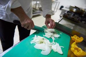 chef in hotel kitchen  slice  vegetables with knife photo
