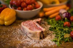 Juicy slice of raw steak on wooden table photo