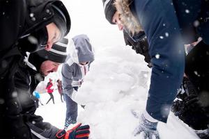 group of young people making a snowman photo