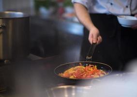 chef volteando verduras en wok foto