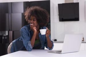 smiling black woman in modern kitchen photo