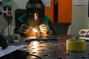 A woman employed in a modern factory for the production and processing of metals in a work uniform welding metal materials photo