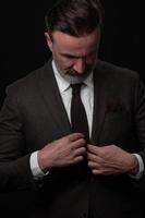 Portrait of a stylish elegant senior businessman with a beard and casual business clothes in photo studio adjusting suit