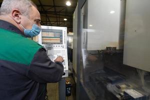 A smart factory worker or engineer wears a face mask because of a pandemic and makes machines in a production workshop. The concept of industry and engineering. photo