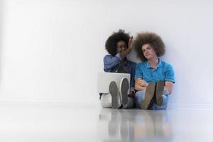 multiethnic couple sitting on the floor with a laptop and tablet photo