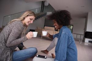 young multiethnic women sit on the floor and drinking coffee photo