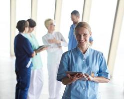 female doctor with tablet computer  standing in front of team photo