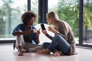 multiethnic women sit on the floor and drinking coffee photo