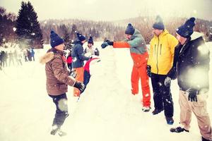 grupo de jóvenes haciendo un muñeco de nieve foto