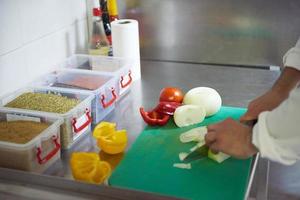 chef in hotel kitchen  slice  vegetables with knife photo