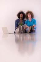 multiethnic couple sitting on the floor with a laptop and tablet photo