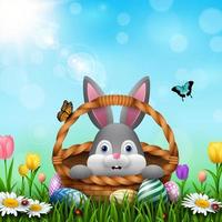 Cute Easter bunny in a basket with colorful eggs on the grass