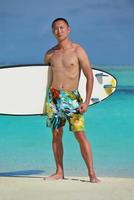 Man with surf board on beach photo