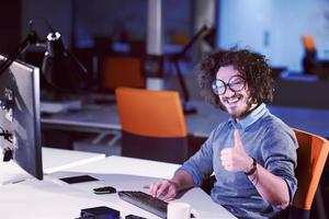 hombre trabajando en una computadora en una oficina de inicio oscura foto