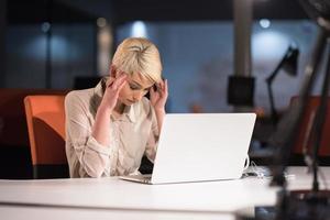 mujer que trabaja en la computadora portátil en la oficina de inicio de la noche foto