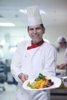 chef en la cocina del hotel preparando y decorando comida foto