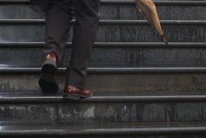 business executive climbing up stairs with umbrela in his hand photo