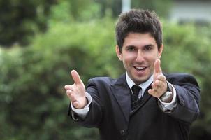 Young caucasian business man in a suite, pointing at camera to y photo