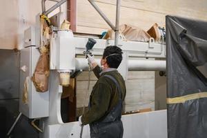 un trabajador pintando una pieza mecánica con spray sin aire foto