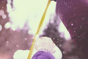 young people measuring the height of finished snowman photo