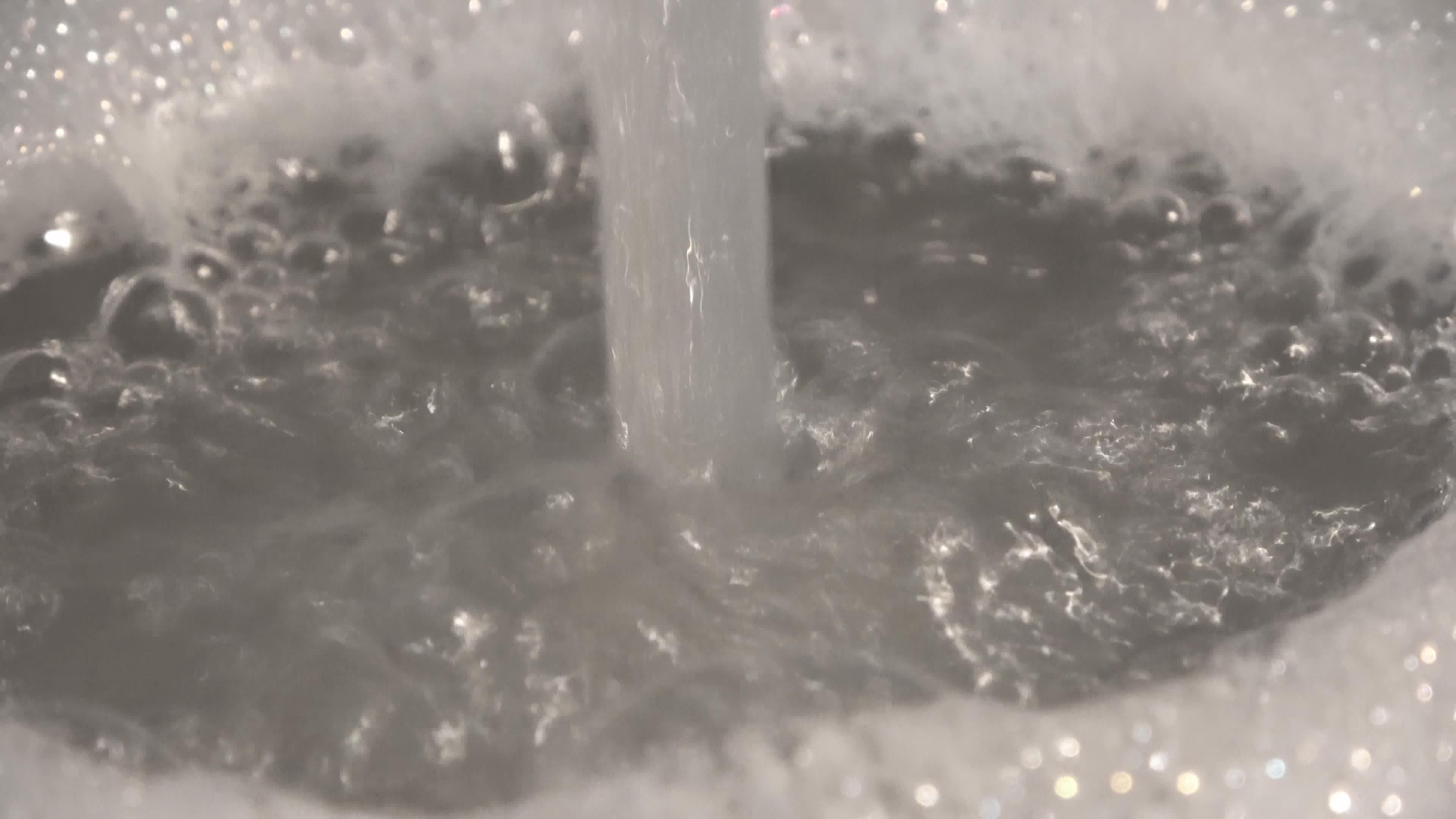 Foam and soap bubbles from water in a sink with water running from a water tap