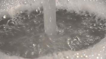 mousse et bulles de savon de l'eau dans un évier avec de l'eau qui coule d'un robinet d'eau. video