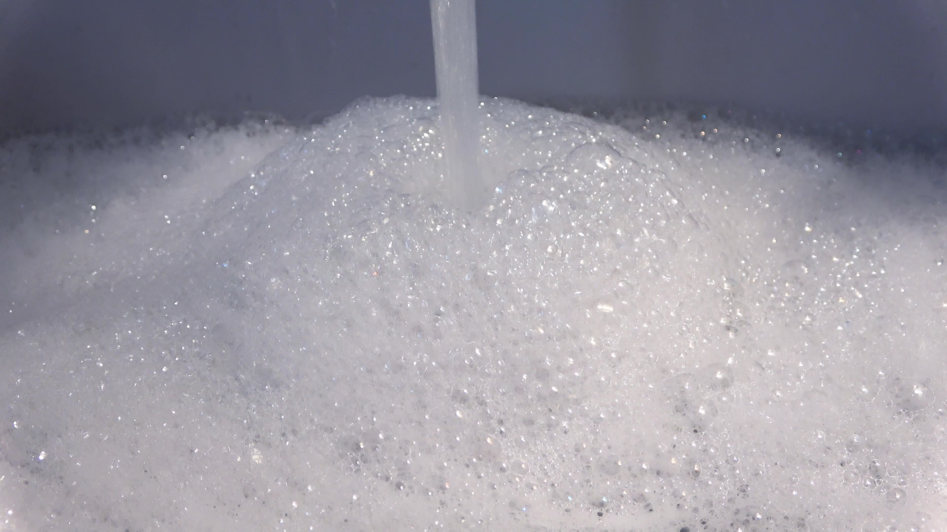 Foam and soap bubbles from water in a sink with water running from a water tap 12086003 Stock