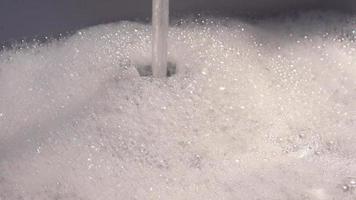 espuma y pompas de jabón del agua en un fregadero con agua que sale de un grifo de agua. video