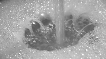 Schaum und Seifenblasen aus Wasser in einem Waschbecken mit Wasser aus einem Wasserhahn. video