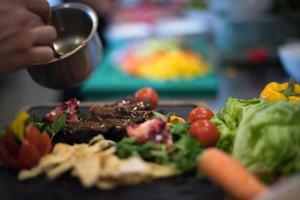 Chef hand finishing steak meat plate photo