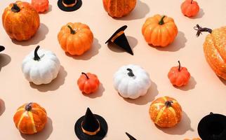 patrón de coloridas calabazas artificiales y sombreros de halloween sobre fondo naranja foto
