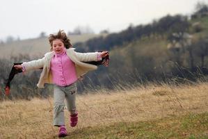 hermosa chica corriendo en la pradera con viento en el pelo foto