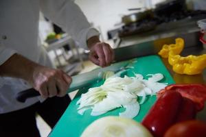 chef in hotel kitchen  slice  vegetables with knife photo