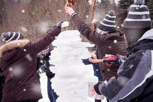 group of young people making a snowman photo