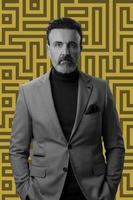 Black and white portrait of a stylish elegant senior businessman with a beard and casual business clothes against retro colorful pattern design background gesturing with hands photo