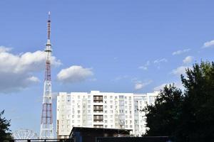 una antena de telecomunicaciones en la ciudad y una noria con una casa grande y un cielo azul. foto