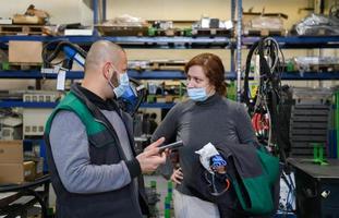 Industrial workers with face masks protected against corona virus discussing about production in factory. People working during COVID-19 pandemic. photo