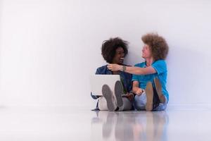 multiethnic couple sitting on the floor with a laptop and tablet photo