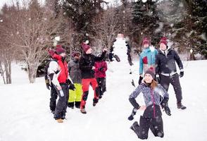 group portait of young people posing with snowman photo