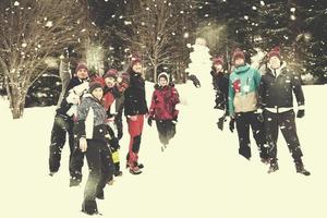 group portait of young people posing with snowman photo