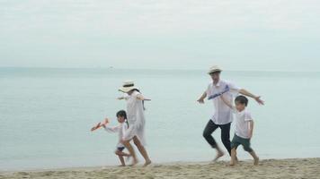 feliz família asiática se divertindo e alegre com o braço esticado mesmo um avião na praia em férias para relaxar, pai e mãe e lazer infantil no conceito de verão, férias e viagens. video