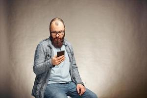 mobile technology and digital device addiction. smiling man holding phone. photo